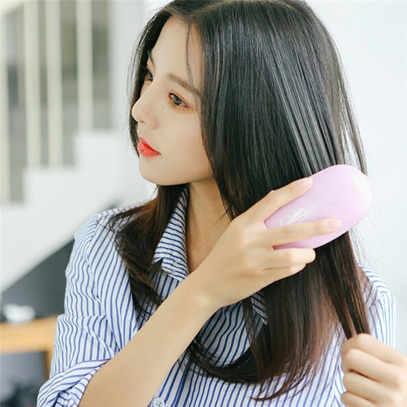 Using the electric hairbrush to smooth long frizzy hair